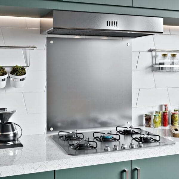 Angled view of a stainless steel splashback mounted behind a stove in a kitchen with green cabinets